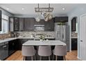 Modern kitchen featuring an island, stainless steel appliances, dark cabinets, tiled backsplash, and hardwood floors at 13322 Meadow Park Ln, Broomfield, CO 80020