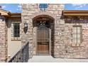 Inviting stone entryway with a secure screen door, brick archway, and classic wrought iron accents at 2317 Primo Rd # A, Highlands Ranch, CO 80129
