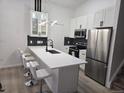 Modern kitchen featuring white cabinets, stainless steel appliances, and a breakfast bar with seating at 17605 E Temple Dr, Aurora, CO 80015