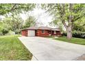 Quaint single-story red brick home boasts a spacious driveway, lush greenery, and an attached garage at 6340 Quay St, Arvada, CO 80003