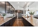 Modern kitchen with stainless steel appliances, granite countertops, dark cabinets, and hardwood floors for a sleek design at 14419 Dahlia St, Thornton, CO 80602