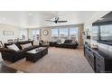 Bright living room with large windows, two sofas, a ceiling fan, fireplace, and an adjacent dining area at 14419 Dahlia St, Thornton, CO 80602