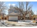 Two story home with a brick-accented front, driveway, basketball hoop, and well-maintained lawn with winter snow at 13277 Elizabeth St, Thornton, CO 80241