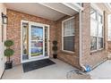 Charming front porch with brick siding, a secure door, and manicured greenery on either side at 13277 Elizabeth St, Thornton, CO 80241