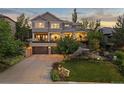 Beautiful home featuring a manicured lawn, mature trees, and an attached three-car garage at 1102 Buffalo Ridge Rd, Castle Pines, CO 80108