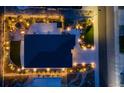 Aerial night view of a home with professional landscape lighting and a patio with a firepit and outdoor kitchen at 4213 Hickory Oaks St, Castle Rock, CO 80104