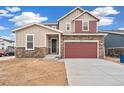 Charming two-story home with stone accents, a two-car garage, and complementary tan and red exterior colors at 20630 E 58Th Ave, Aurora, CO 80019