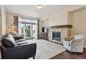 Cozy living room featuring a stone fireplace, a large window, and comfortable seating, perfect for relaxation at 2505 S Orion St, Lakewood, CO 80228