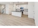 Modern kitchen with white cabinets, granite island, and LVP flooring at 20690 E 58Th Ave, Aurora, CO 80019