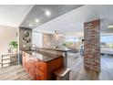 Spacious kitchen area showing wooden cabinets, breakfast bar, brick accent wall, and open floor plan to living spaces at 1625 Larimer St # 2501, Denver, CO 80202