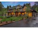 Two-story home with black metal roof, balconies, green lawn, and manicured landscaping at 1298 Meadow View Dr, Evergreen, CO 80439