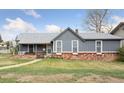 Exterior of a well-maintained home with gray siding, a cozy front porch, and mature landscaping at 4595 S Fox St, Englewood, CO 80110