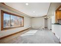 Bright living room features neutral carpet, wood trim, and large window at 11782 Gilpin St, Northglenn, CO 80233