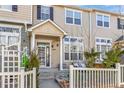 Charming two-story townhome with a covered entry, white picket fence, and well-manicured landscaping at 1465 Red Cliff Way, Castle Rock, CO 80109