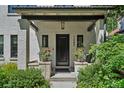 Close up of covered porch with black front door, flower pots, rocking chairs, and the house number at 1265 S Gaylord St, Denver, CO 80210