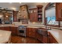 Kitchen featuring custom cabinets, a stone range hood, stainless steel appliances, and a copper sink at 8871 Aspen Leaf Ct, Littleton, CO 80125