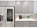 Close-up of kitchen area featuring stainless steel refrigerator, light grey cabinets, and tile backsplash at 1694 Castle Vista Way, Castle Rock, CO 80104