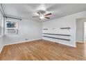 Bright living room featuring hardwood floors, built-in shelving, and a ceiling fan at 740 Fulton Ave, Fort Lupton, CO 80621