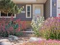 Close up of the home's front entrance surrounded by beautiful landscaping and colorful flowers at 2155 S Deframe St, Lakewood, CO 80228