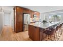 This renovated kitchen features stainless steel appliances, wood cabinets, granite counters, and an island with seating at 2155 S Deframe St, Lakewood, CO 80228