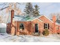 Quaint brick home featuring a chimney and small front yard on a sunny, winter day at 1117 Jersey St, Denver, CO 80220