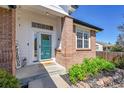 Inviting front porch with brick pillar, landscaped garden, door with screen, and a glimpse into the home at 12408 W 83Rd Ave, Arvada, CO 80005