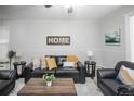 Comfortable living room with a stylish black leather sofa, accent chairs, and a decorative HOME sign at 136 W Maple Ave, Denver, CO 80223