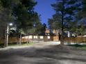 A cozy home at night, softly lit with a modern fence, set amongst mature trees and nestled on a spacious lot at 34480 County Road 17, Elizabeth, CO 80107