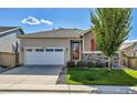 Inviting single-story home featuring a two-car garage, well-kept lawn, and attractive stone detailing at 27862 E 9Th Dr, Aurora, CO 80018