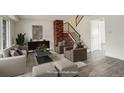 Bright living room with brick accent wall, staircase, and neutral decor, virtually staged at 13015 W Ohio Ave, Lakewood, CO 80228