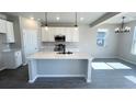 Modern kitchen featuring white cabinets, a large island, stainless steel appliances, and stylish pendant lighting at 2303 Peregrine Dr, Brighton, CO 80601