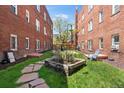 A quaint backyard featuring a garden bed and green space between two brick buildings at 1351 N Washington St # 15, Denver, CO 80203