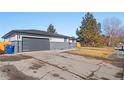 View of home's side yard and gray garage with modern-look door at 8217 W 71St Pl, Arvada, CO 80004