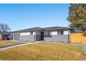 Charming gray brick and siding home with well-manicured lawn at 8217 W 71St Pl, Arvada, CO 80004