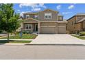 Inviting two-story home with a combination of stone and siding, an attached two-car garage, and a green front yard at 887 Sundance Ln, Erie, CO 80516