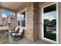 Inviting covered porch with stacked stone columns and seating area with views of the street at 887 Sundance Ln, Erie, CO 80516