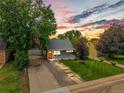 Exterior shot of inviting gray home with landscaped front yard and glowing walkway lights at dusk at 2535 S Julian St, Denver, CO 80219