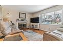 Cozy living room features hardwood floors, a brick fireplace, and a large window with neighborhood views at 1744 S Leyden St, Denver, CO 80224