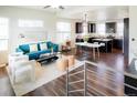 Open-concept living room and kitchen with modern furnishings and dark wood floors at 8953 E Northfield Blvd, Denver, CO 80238