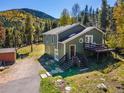 Charming two-story home featuring a deck, lush landscaping, and scenic mountain views at 32252 Steven Way, Conifer, CO 80433