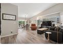 Bright living room with vaulted ceiling, hardwood floors, and sliding glass doors to patio at 9747 W Peakview Dr, Littleton, CO 80123
