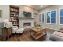 Inviting living room with stone fireplace, built-in shelves, hardwood floors, and natural light from the windows at 3242 Waterfront Dr, Monument, CO 80132