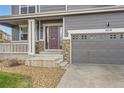 Close up of front entrance with gray garage door and front porch with white railings and concrete steps at 14110 Greenfield Loop, Parker, CO 80134