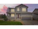 Charming gray two-story home featuring a welcoming front porch and well-manicured lawn and a two car garage at 14110 Greenfield Loop, Parker, CO 80134