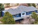 Rear exterior view of a well-maintained blue home with a spacious deck and mature trees at 2130 Frontier Ln, Franktown, CO 80116