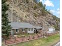 Attractive stone home with a covered parking area, complemented by a rustic fence and mountain views at 4364 Colorado 103, Idaho Springs, CO 80452