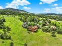 Expansive aerial view of a wood home nestled in a lush green valley with mountain views at 953 Gilia Dr, Golden, CO 80401