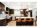 Modern kitchen with dark cabinets, stainless steel appliances, quartz countertops, and pendant lighting at 6325 W Portland Pl, Littleton, CO 80128