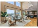 Bright living room with large windows, wood floors, comfortable seating, and access to kitchen and outdoor deck at 6614 W Gould Dr, Littleton, CO 80123