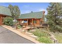 Charming cabin with a quaint wooden bridge and a serene pond surrounded by natural stone features and verdant foliage at 12191 Tecumseh Trl, Conifer, CO 80433